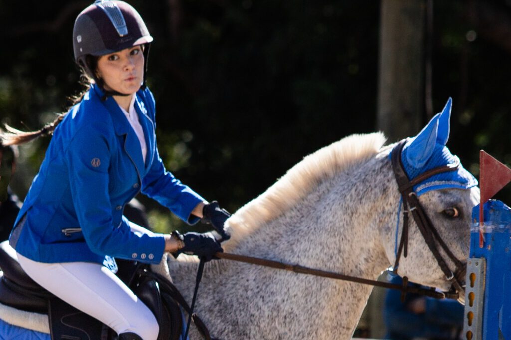 Girl with blue jacket on white horse