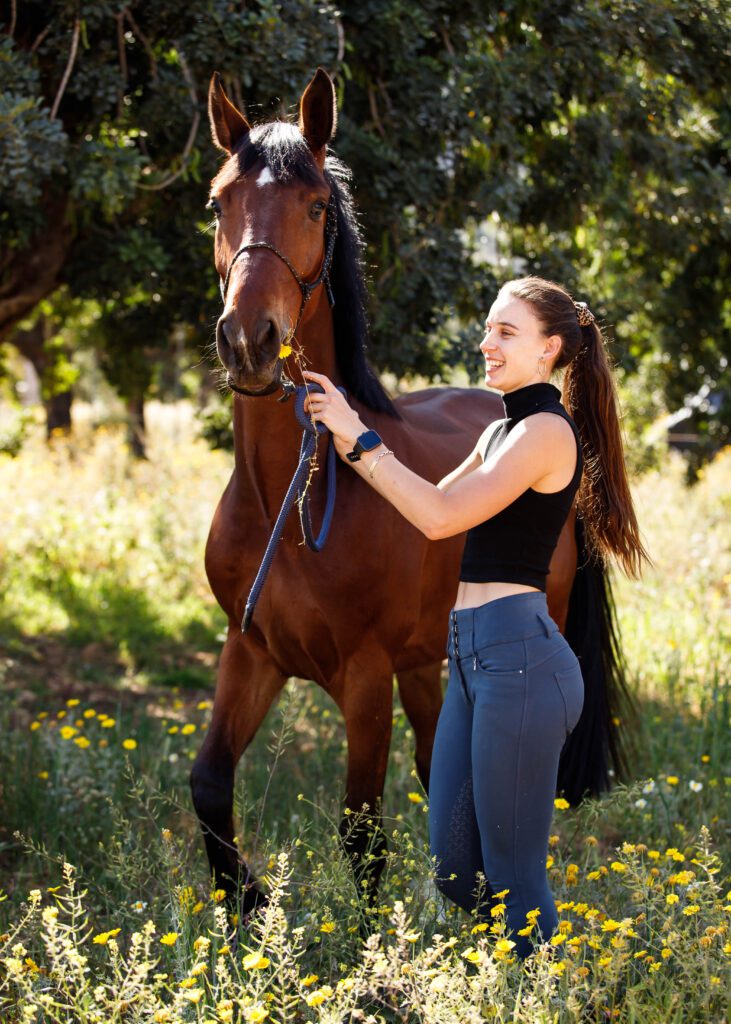 girla and young horse with flowers in m out